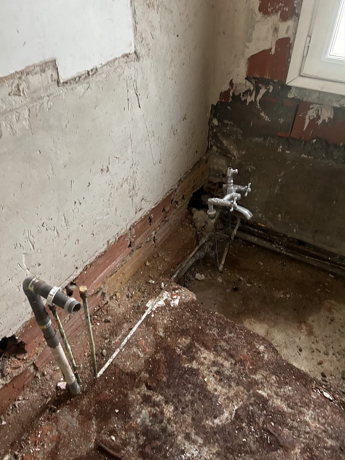 Ancien réseau de plomberie mis à nu, murs décapés avant rénovation