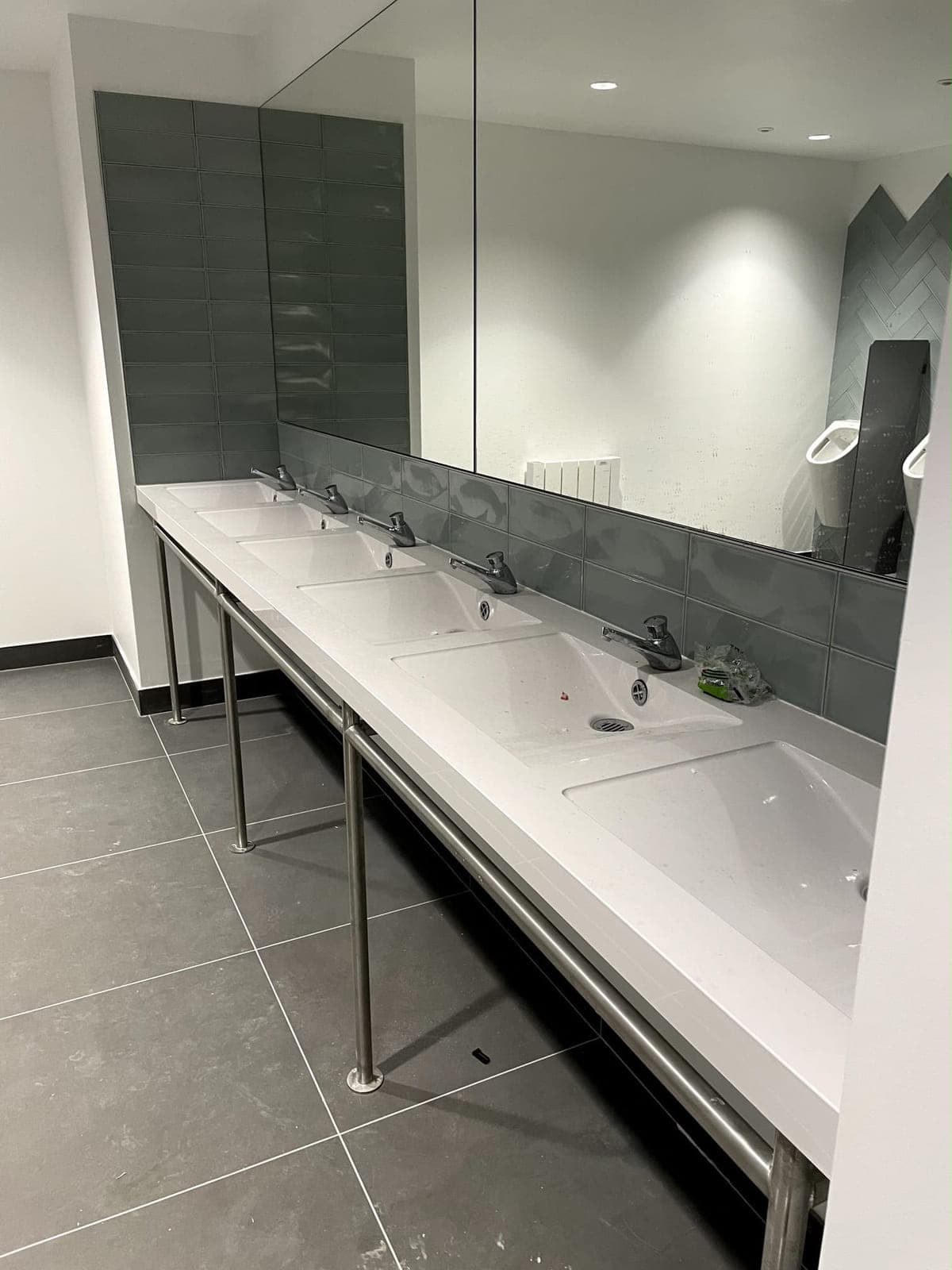 Sanitaires collectifs équipés d'une rangée de vasques sur bâti inox
