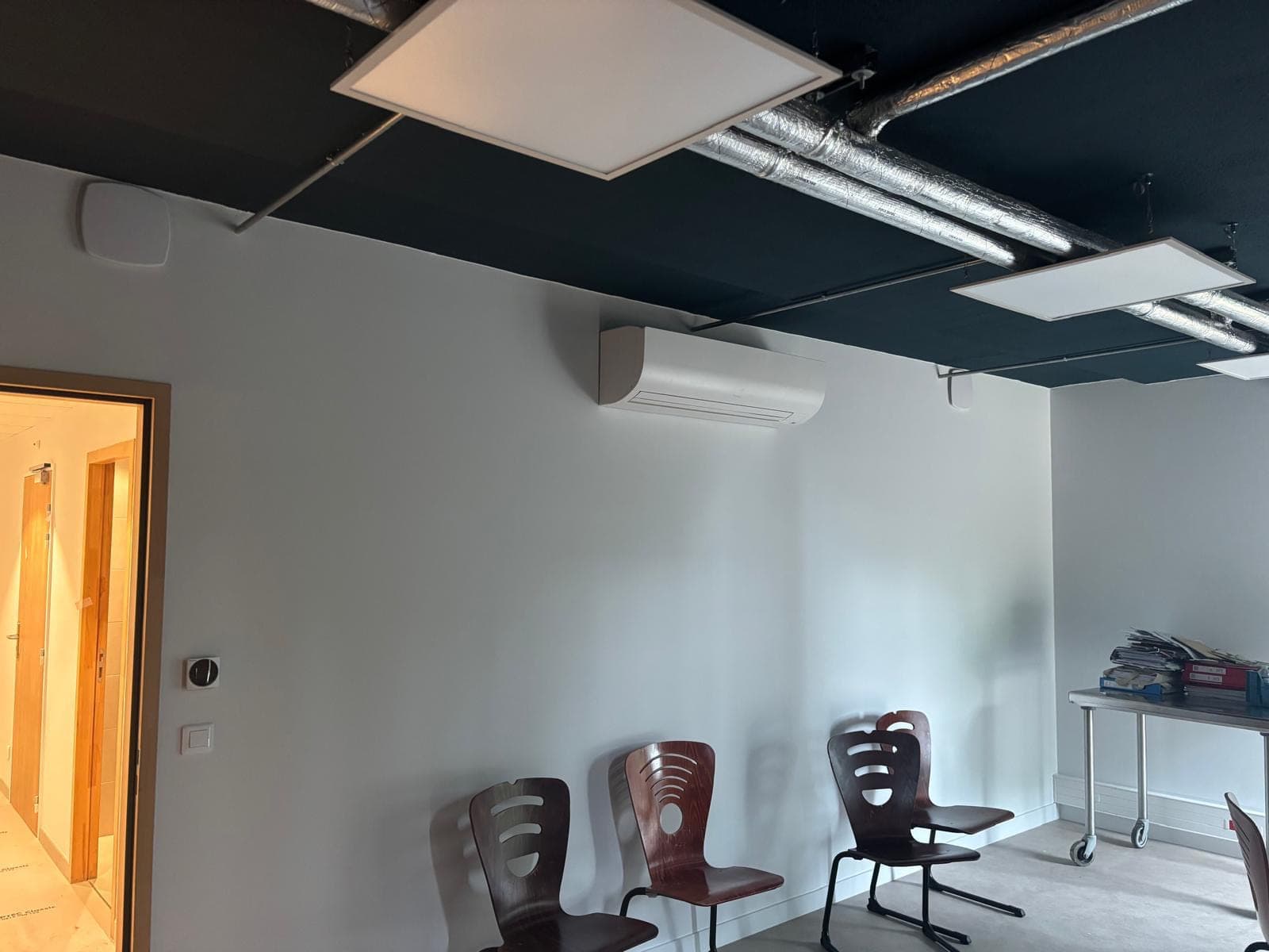 Unité murale de climatisation dans un bureau, gaines et dalles acoustiques au plafond