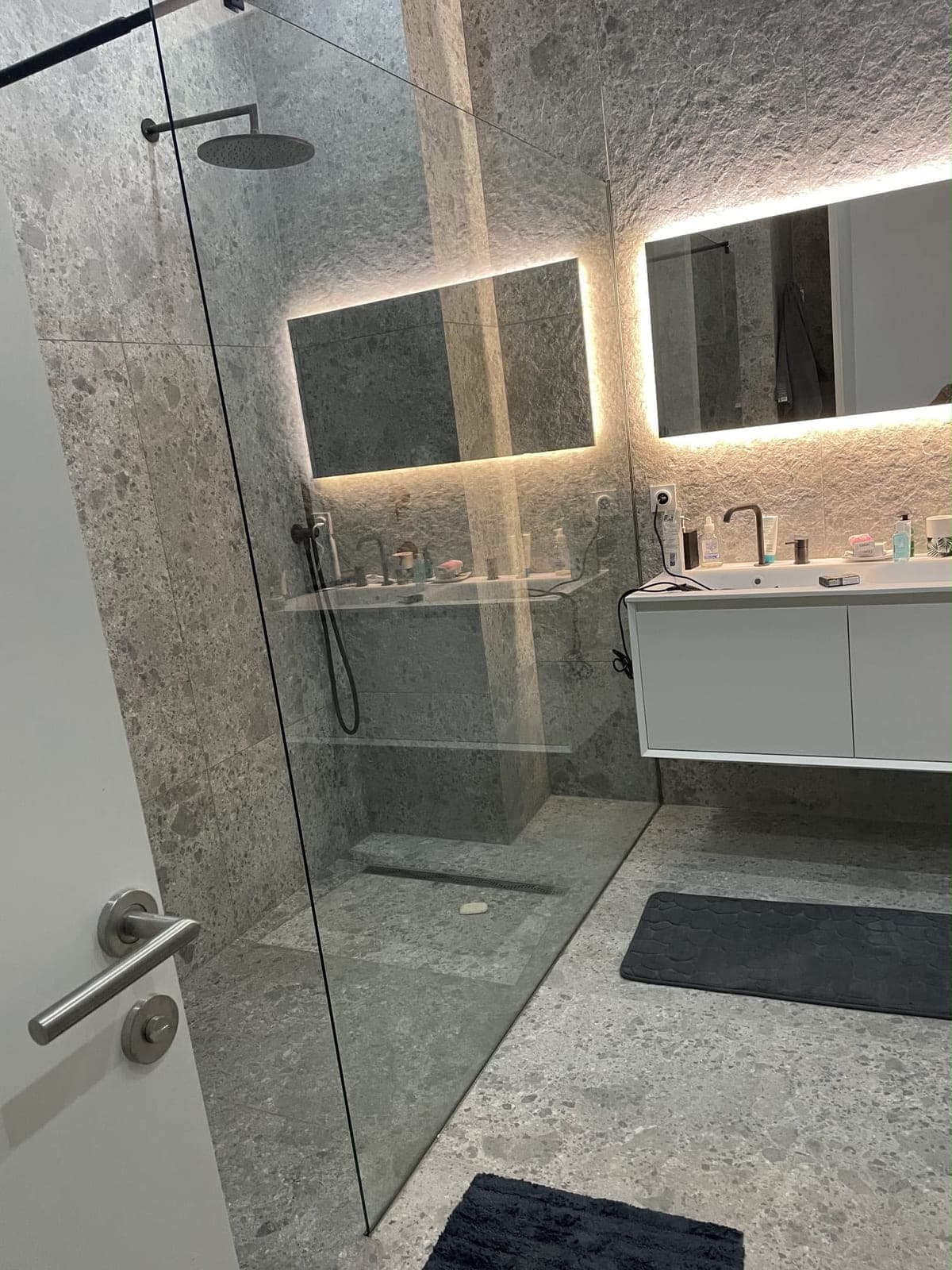 Douche à l'italienne carrelée en pierre grise avec caniveau de sol encastré