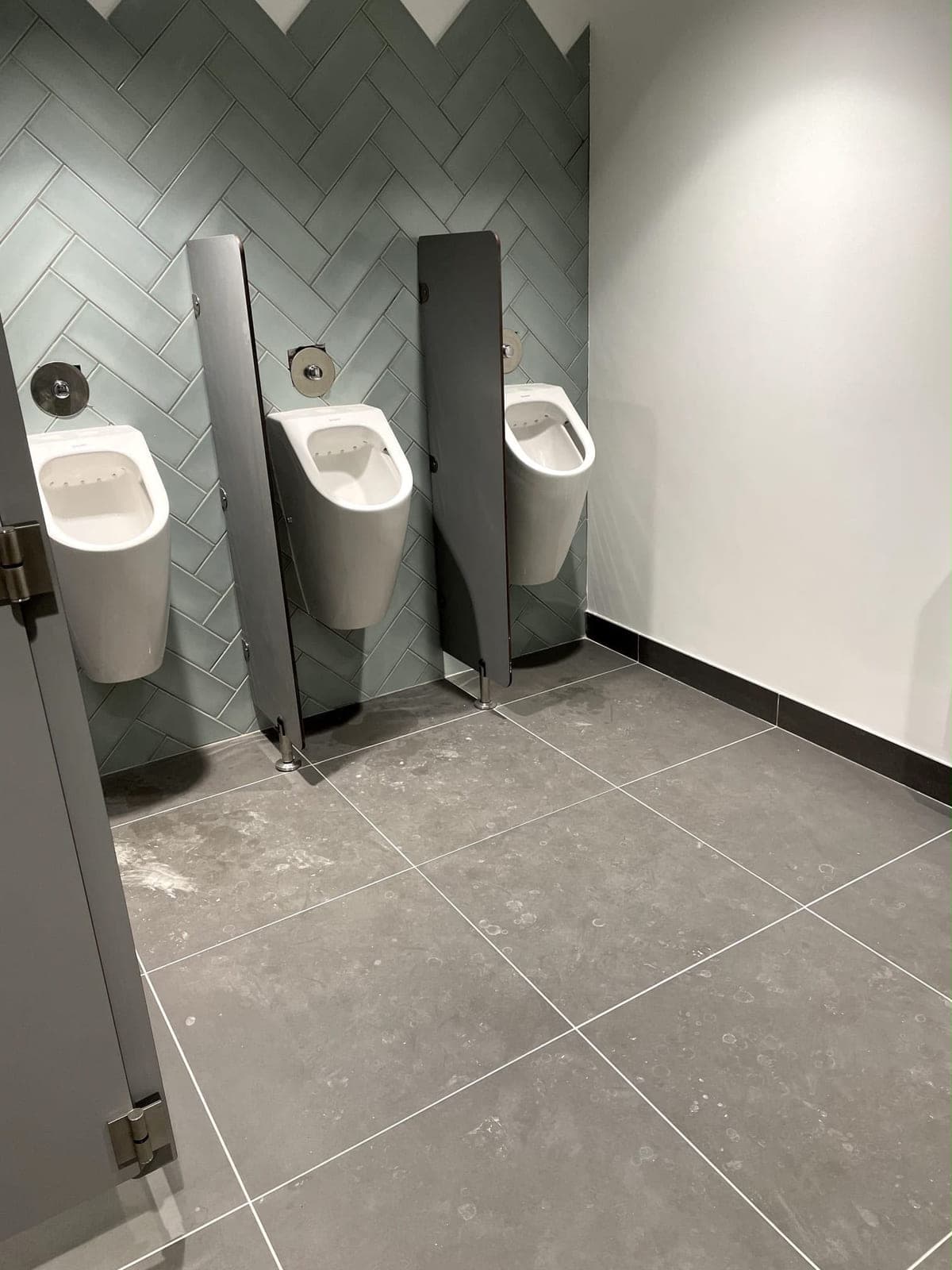 Urinoirs avec séparations dans des sanitaires collectifs, faïence en chevrons