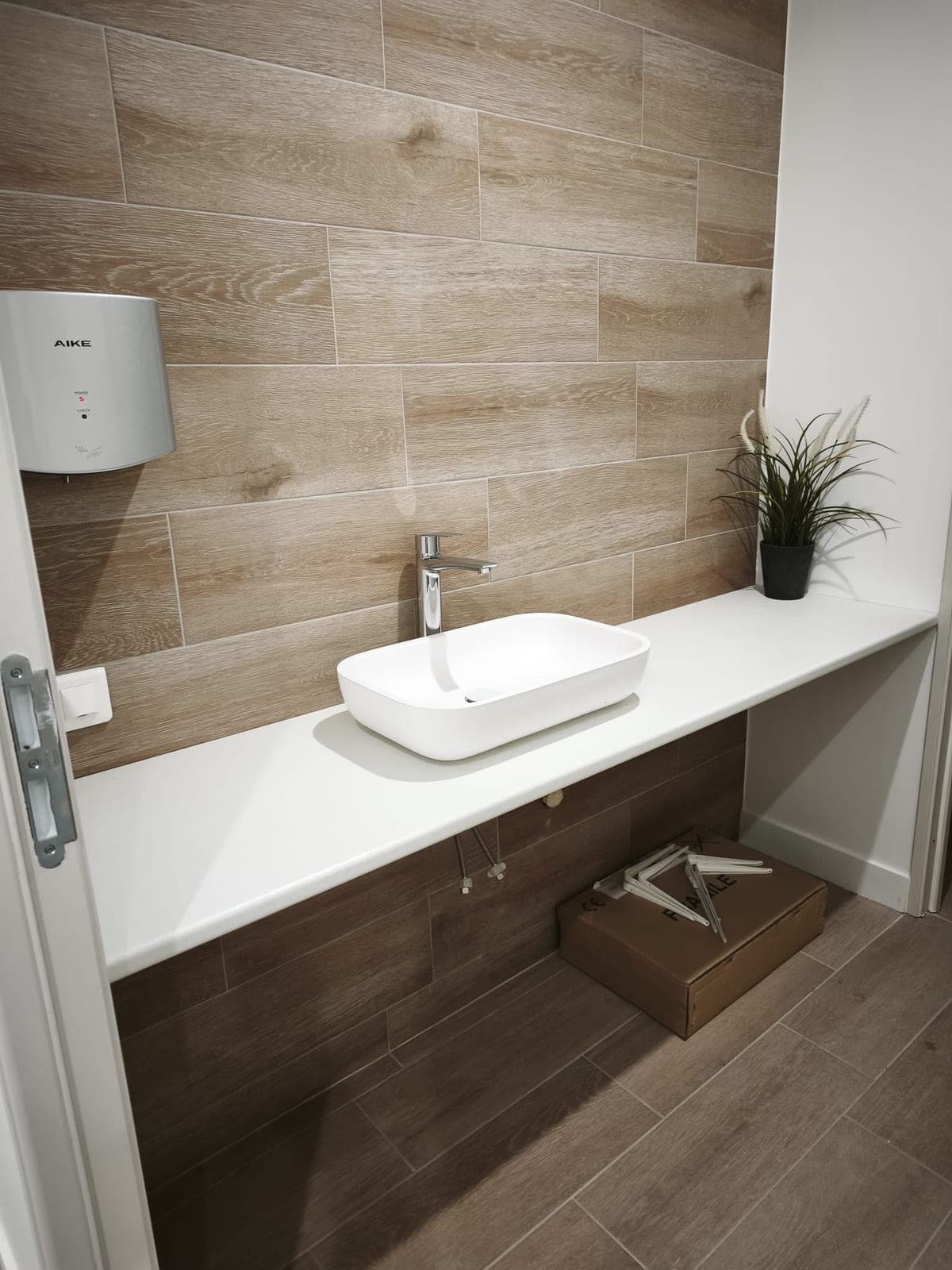 Vasque à poser sur plan blanc et sèche-mains dans des sanitaires professionnels