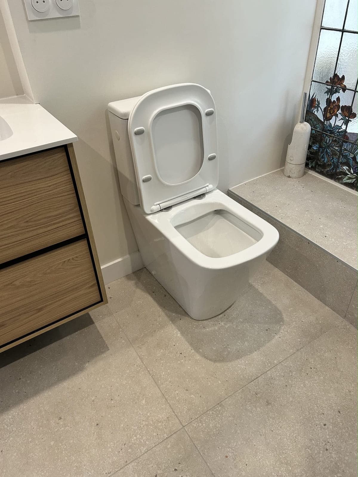 WC posé au sol à côté d'un meuble vasque en bois