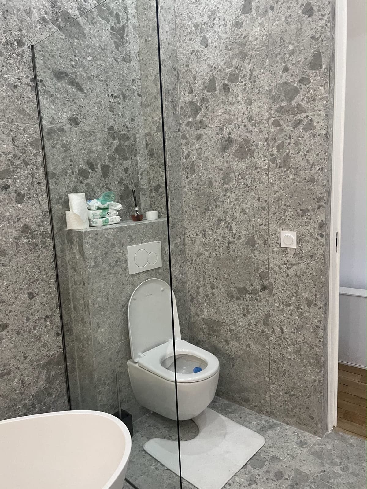 WC suspendu sur bâti-support habillé en pierre grise, avec tablette maçonnée